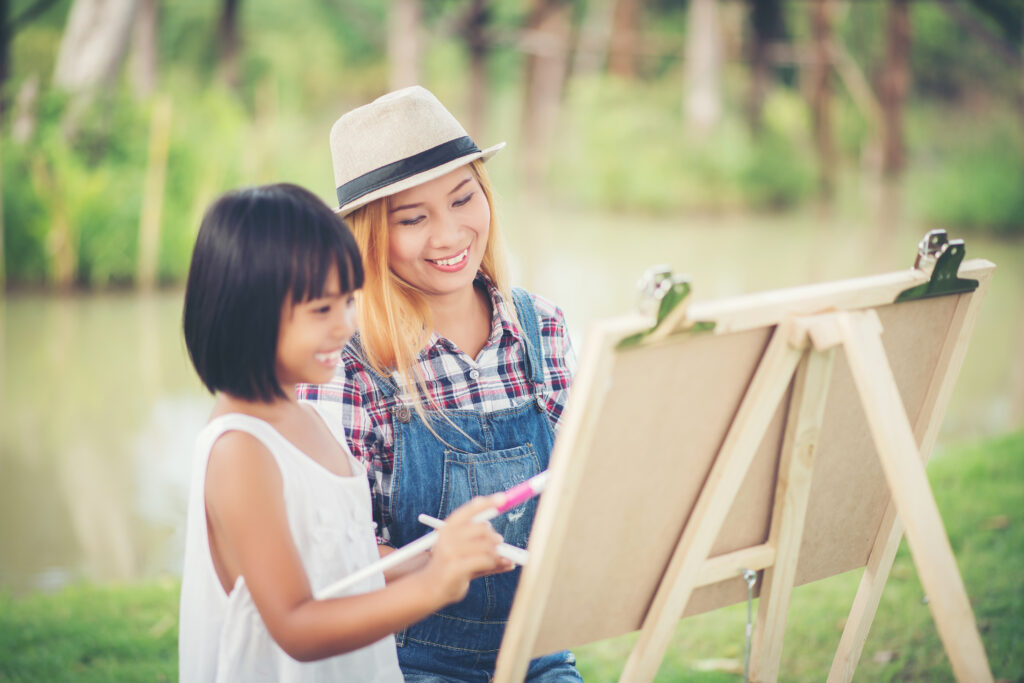 mother and daughter painting at a waterfront location